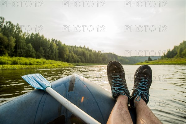 Man resting feet on boat in lake