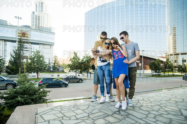 Caucasian couples taking selfie together in city