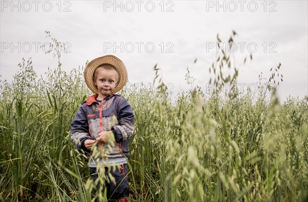 Caucasian boy standing in tall grass in rural field