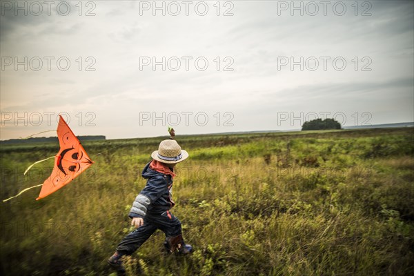 Caucasian boy flying kite in rural field