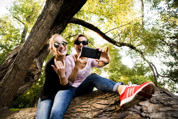 Caucasian women taking cell phone selfie in tree