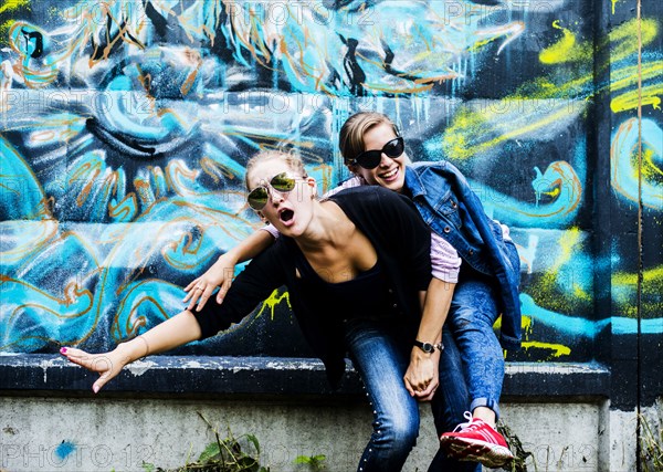 Caucasian women posing near graffiti wall