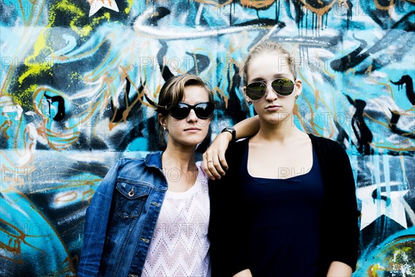 Caucasian women posing near graffiti wall