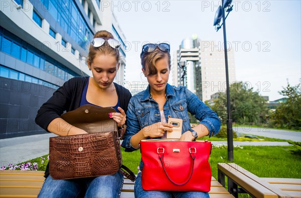 Caucasian women searching in purses on park bench