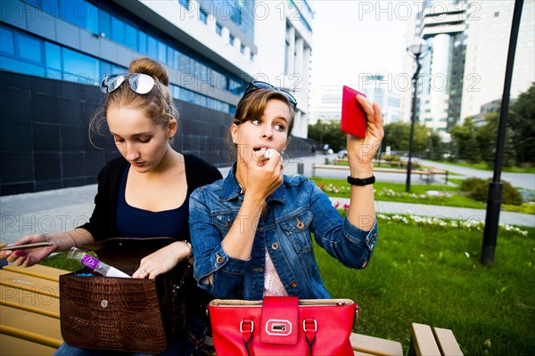 Caucasian woman applying makeup on park bench