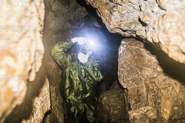 Caucasian man taking photograph in rock formation cave