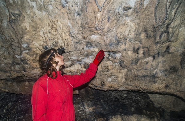 Caucasian woman admiring rock formations in cave