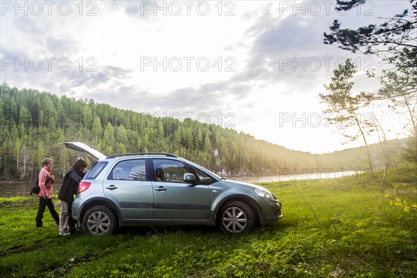 Caucasian tourists unloading car in remote landscape