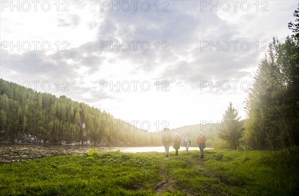 Caucasian tourists walking near river in remote landscape