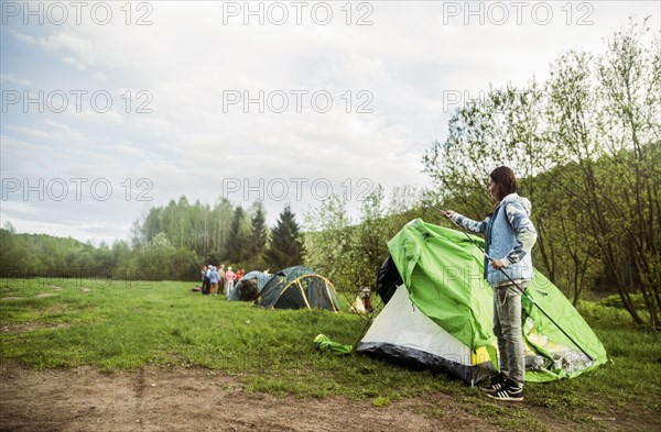 Caucasian camper assembling tent in remote field