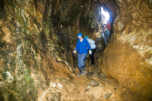 Caucasian people exploring rock formation cave