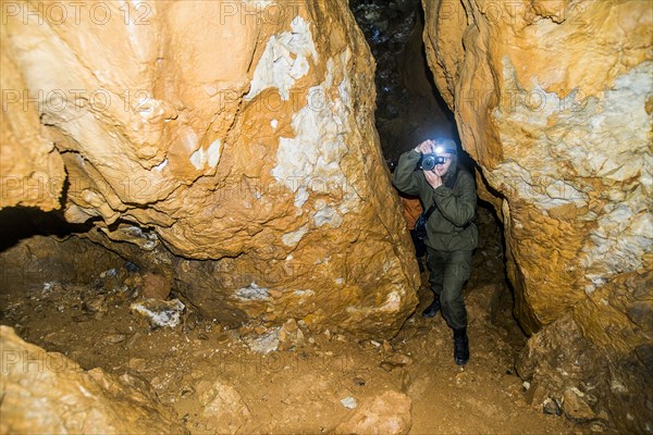 Caucasian man taking photograph in rock formation cave