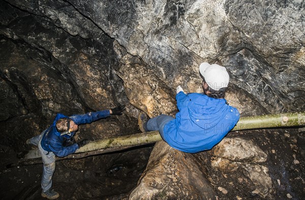 Caucasian climbers exploring rock formation cave