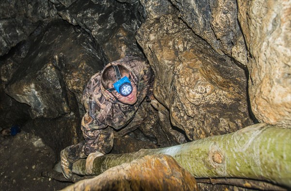 Caucasian climber exploring rock formation cave