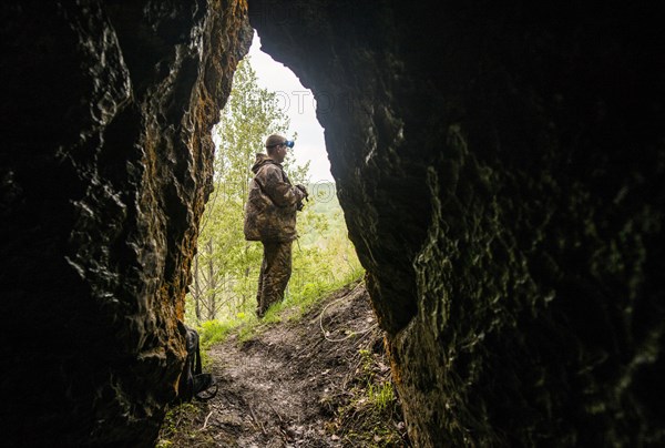 Caucasian man standing outside rock formation cave