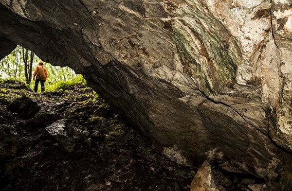 Caucasian woman standing outside rock formation cave