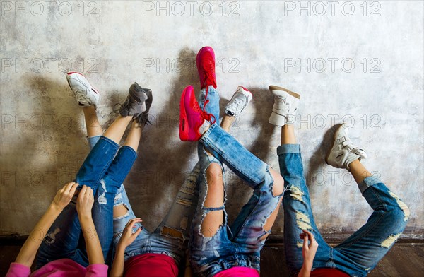 Caucasian women admiring their sneakers against wall