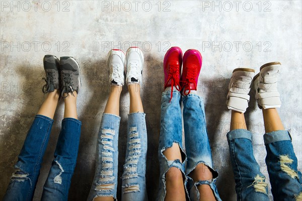 Caucasian women admiring their sneakers against wall