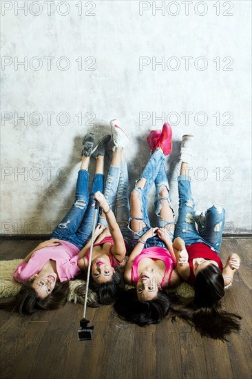 Caucasian women taking cell phone selfie on floor
