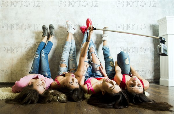 Caucasian women taking cell phone selfie on floor