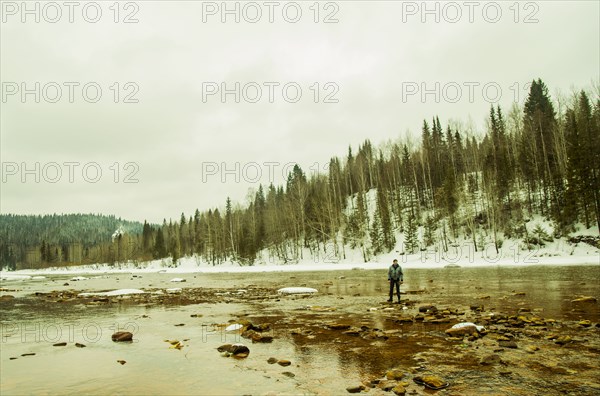 Caucasian hiker standing in rocky remote river