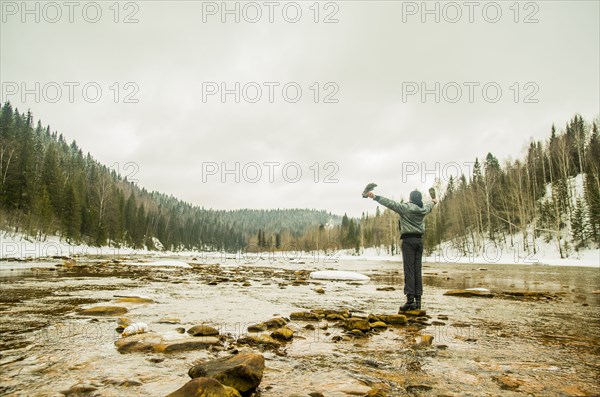 Caucasian hiker with arms outstretched standing in remote river