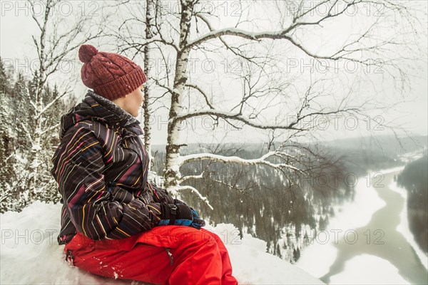 Caucasian hiker sitting on snowy hilltop