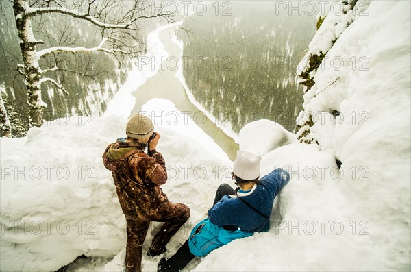 Caucasian hikers enjoying view from snowy hilltop