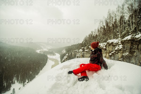 Caucasian hiker sitting on snowy hilltop