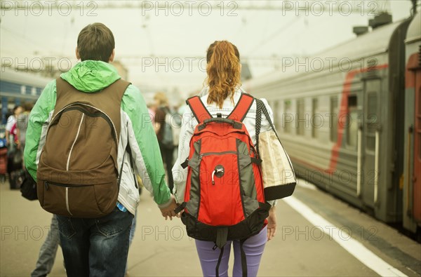 Caucasian couple holding hands on train station platform