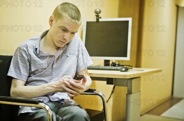 Caucasian man using cell phone at computer desk