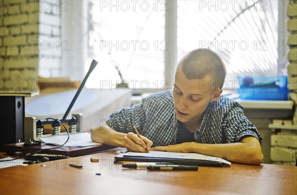 Caucasian artist drawing at studio desk