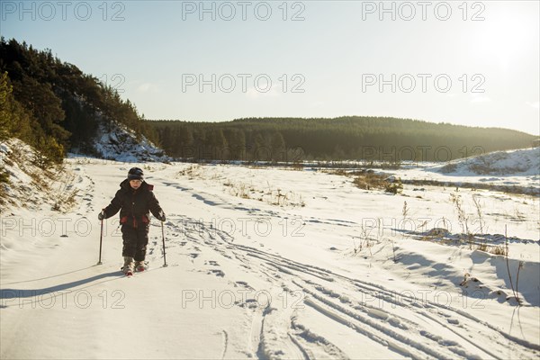 Caucasian boy cross-country skiing in snowy field