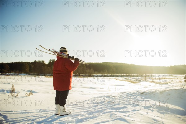 Caucasian woman carrying skis in snowy field