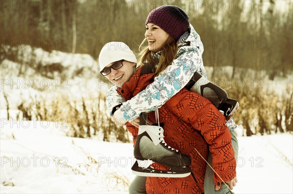 Caucasian couple carrying ice skates in snowy field