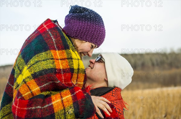 Caucasian couple wrapped in blankets outdoors