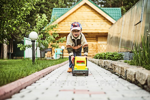 Caucasian boy playing with toy truck in backyard