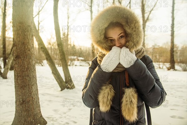 Caucasian woman wearing fur hood and coat in snowy field