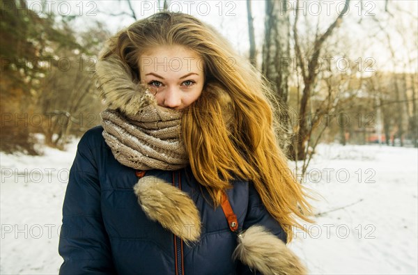 Caucasian woman wearing fur hood and coat in snowy field