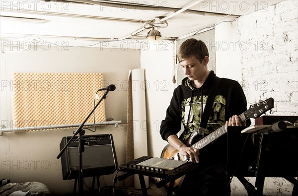 Caucasian man playing electric guitar in rock band