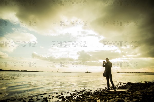 Caucasian tourist photographing rocky beach