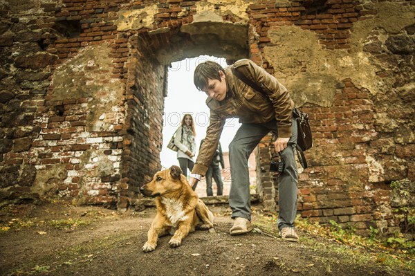 Caucasian man petting dog near ruins