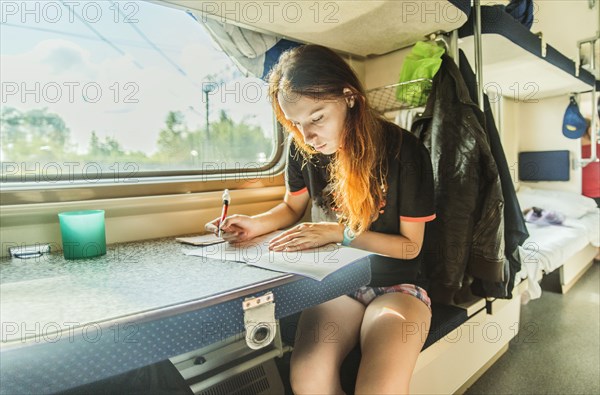 Caucasian girl writing on train