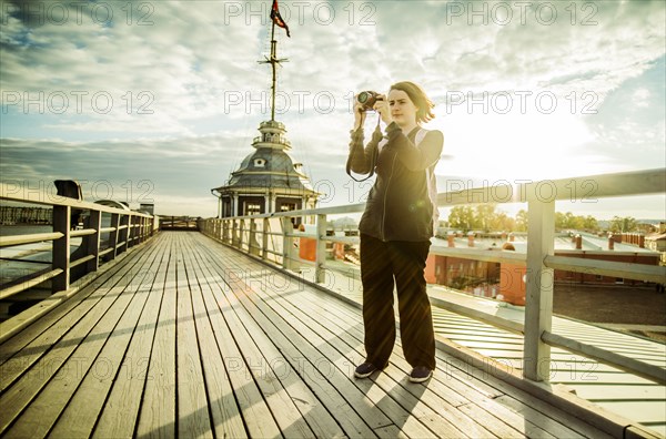 Caucasian tourist using camera on boardwalk