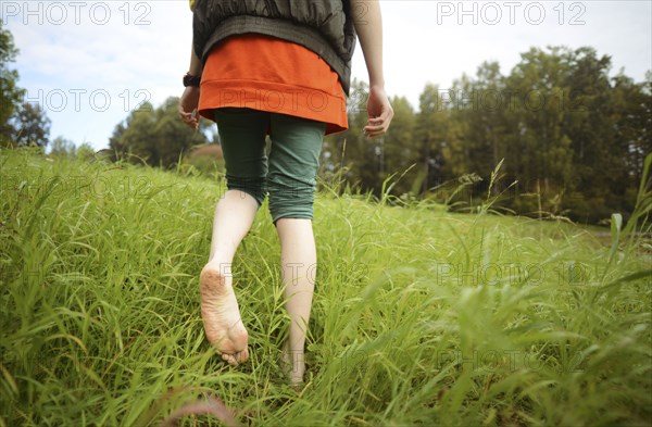 Close up of barefoot Caucasian woman walking in park