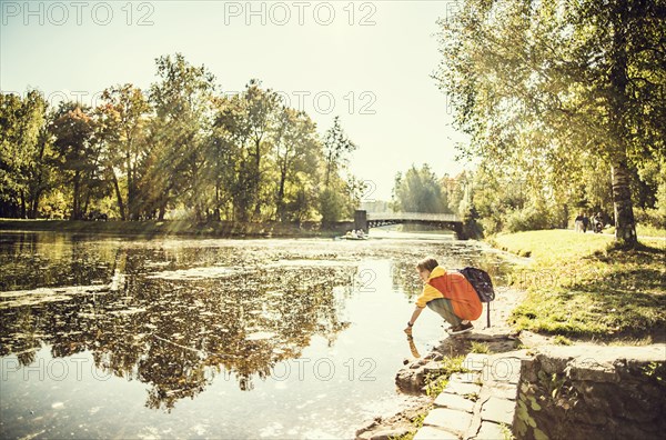 Caucasian woman dipping hand in park pond