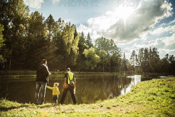 Caucasian father and sons playing near park pond