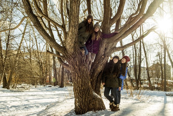 Caucasian girls smiling at tree in snowy field