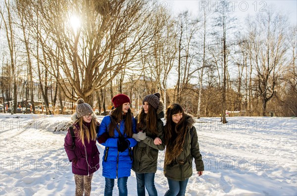 Caucasian girls arm in arm in snowy field