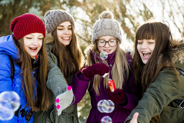 Caucasian girls blowing bubbles outdoors in winter